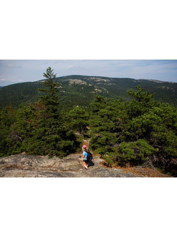 Visitor hikes down exposed granite section of trail