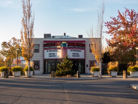 Color Photograph of a two story brick building with a colorful marquee displaying text.
