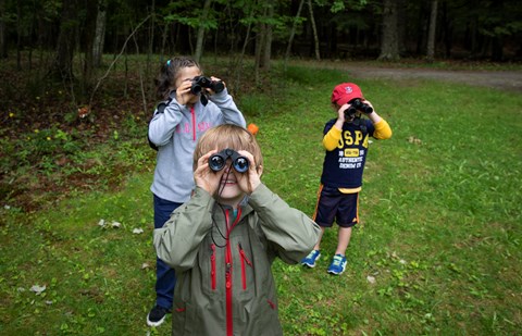 Three children hold up binoculars to watch wildlife in Acadia National Park.