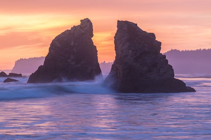 Sunset at a beach with rocky sea stacks and lavender water