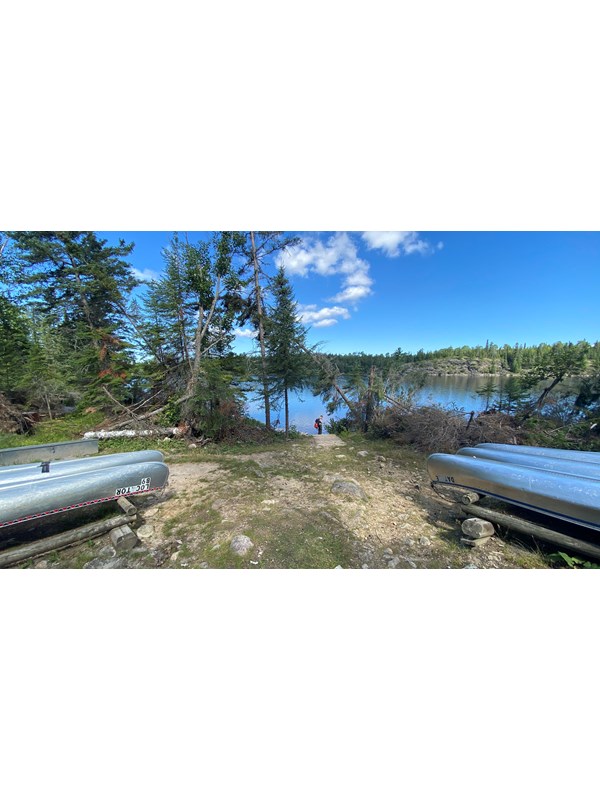 Canoe launch area with two rack of canoes and Locator Lake in background.