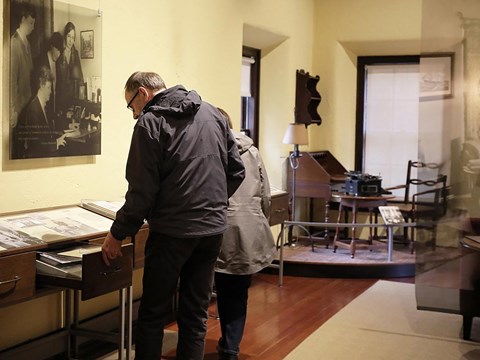 A man and woman open a drawer to see artifacts displayed inside.