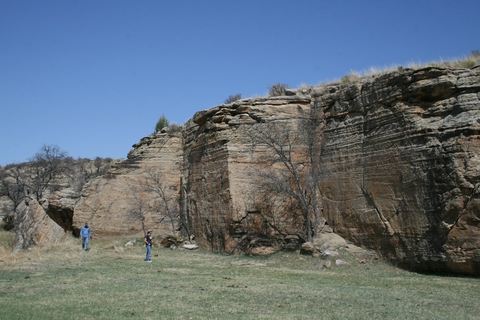A sandstone cliff in a grassy field