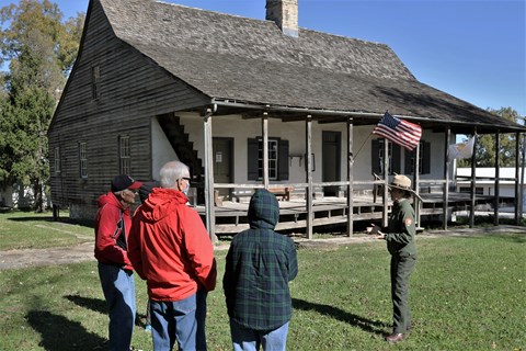 Park Ranger giving a tour in front of a old home with a front porch.
