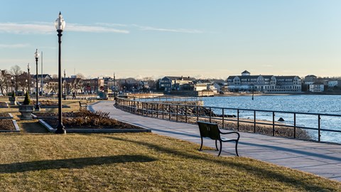 Boardwalk with benches overlooking body of water under blue sky