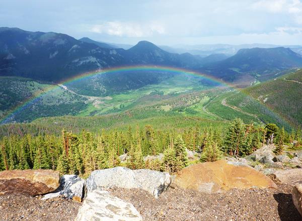 a rainbow spans across the sky, mountains in the distance