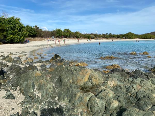 A long white sand beach curves gently around crystal clear turquoise water.