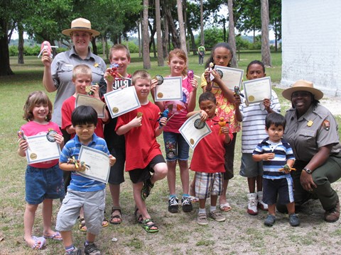 two ranger on either side of group of kids holding certificates