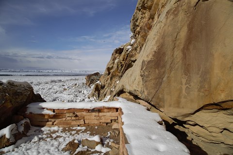 A short stone wall covered in snow offers a place to view petroglyphs and pictographs.