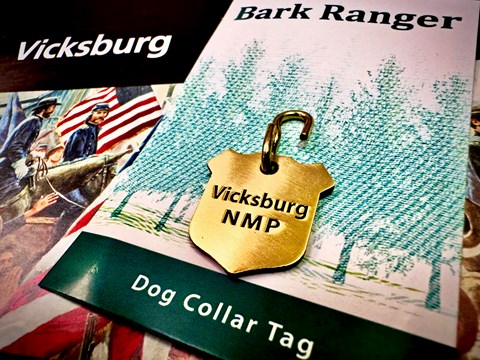 A gold dog tag that reads Vicksburg NMP