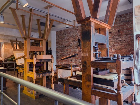 Color image of two wooden 18th-century printing presses with a brick wall in the background.