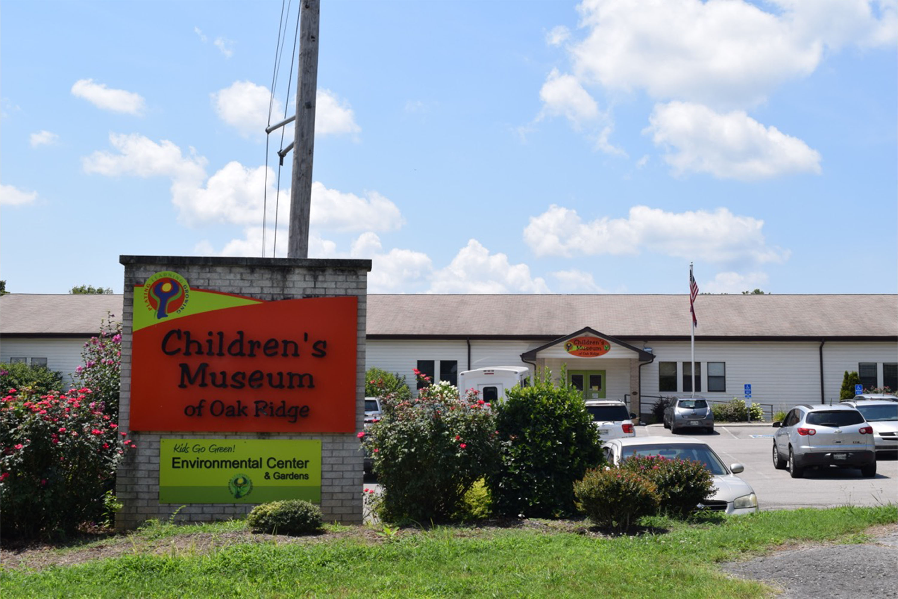 A large sign in front of a parking lot and school building.