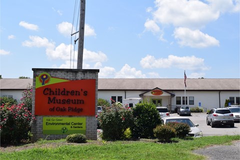 A large sign in front of a parking lot and school building.
