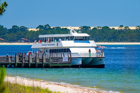 A ferry waits a dock in bright blue water.