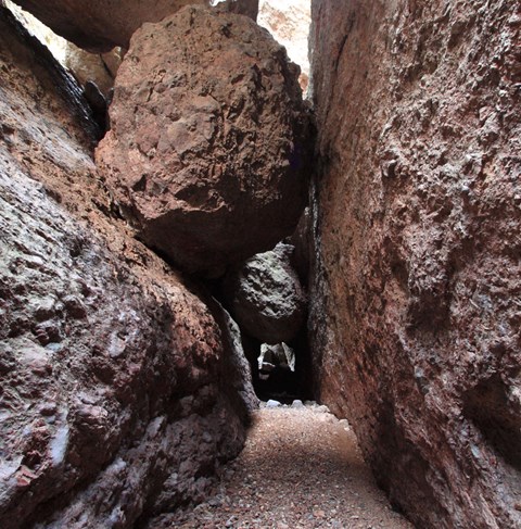 Large boulder wedged in narrow rock canyon.