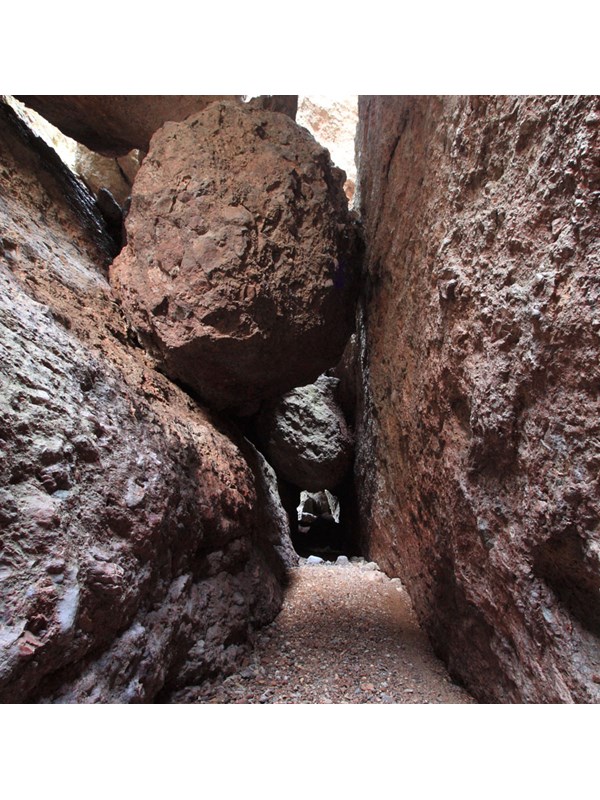 Large boulder wedged in narrow rock canyon.
