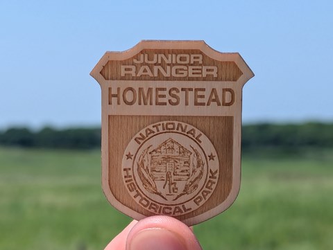 Wooden badge reading "Junior Ranger, Homestead National Historical Park"