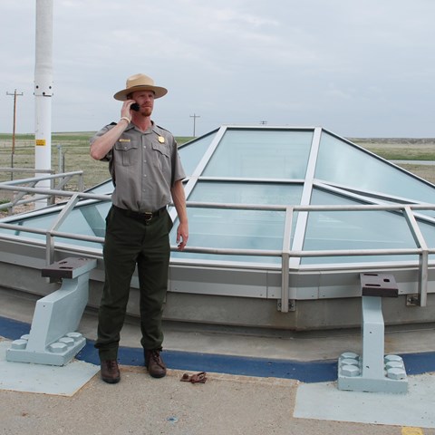 A park ranger stands in front of a glass enclosure at a missile silo