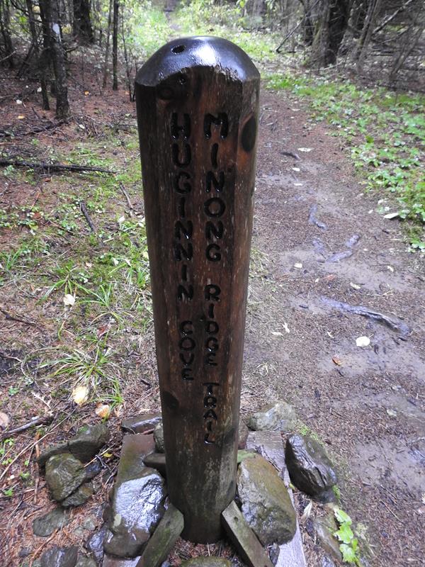 Wooden trail marker for the Minong Ride Trail, surrounded by rocks and forest.