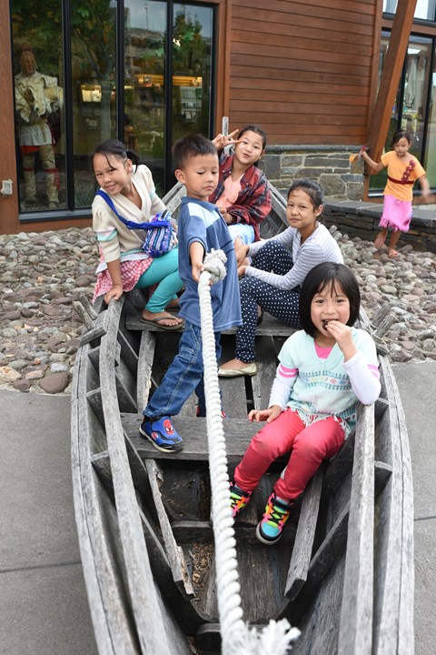 Several kids sit crowded together in a bateau-style boat.