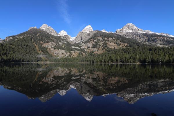 A lake sits at the base of a mountain range with a near perfect reflection on its calm surface.