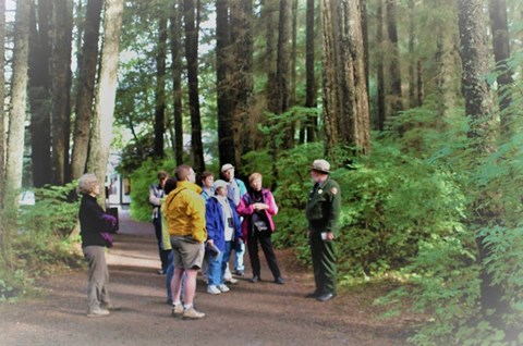 A park ranger speaking with visitors on a forest trail