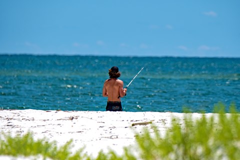 A fisherman stands with his line in the Gulf.