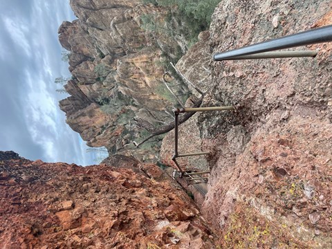 Rocky trail following the edge of a narrow steep rock canyon on stormy afternoon
