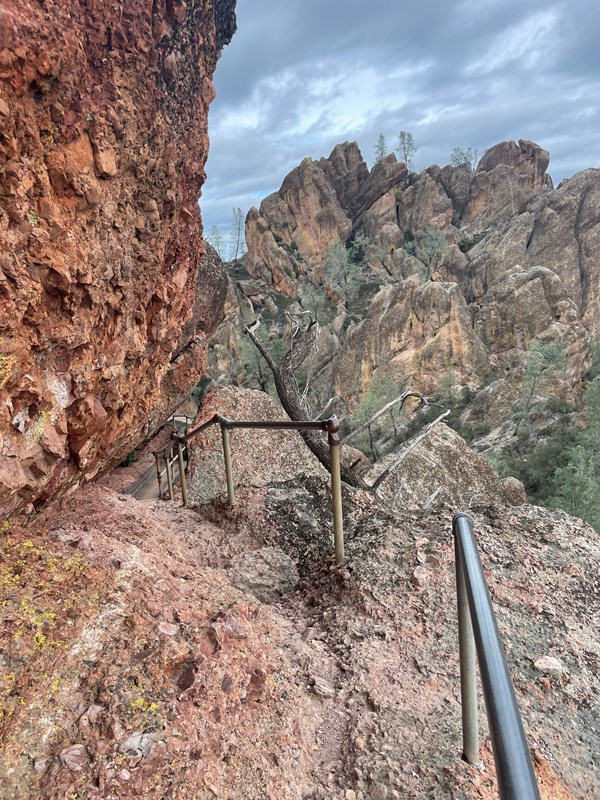 Rocky trail following the edge of a narrow steep rock canyon on stormy afternoon