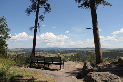 A bench along a trail overlooking a valley.