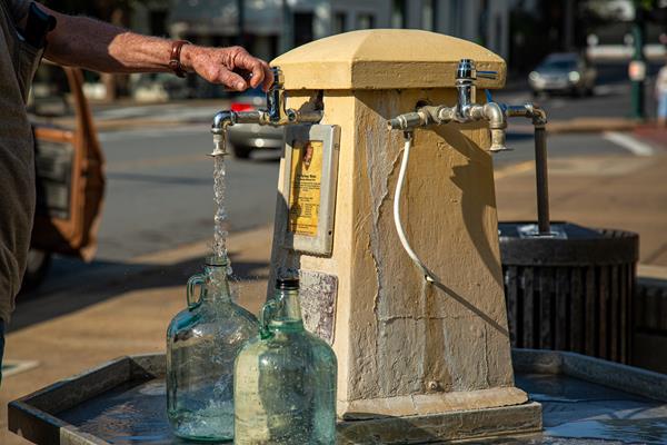 Person filling up glass water jugs.