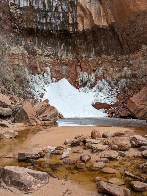 A mound of ice and snow surrounded by red sandstone rocks.