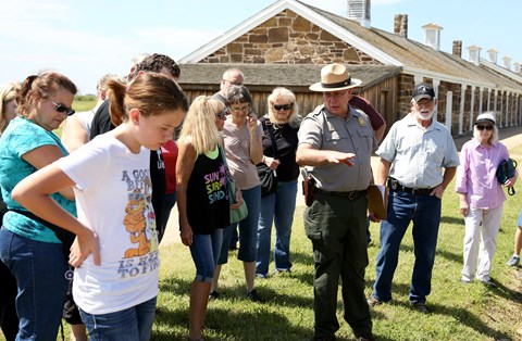 People standing around park ranger in uniform who is talking