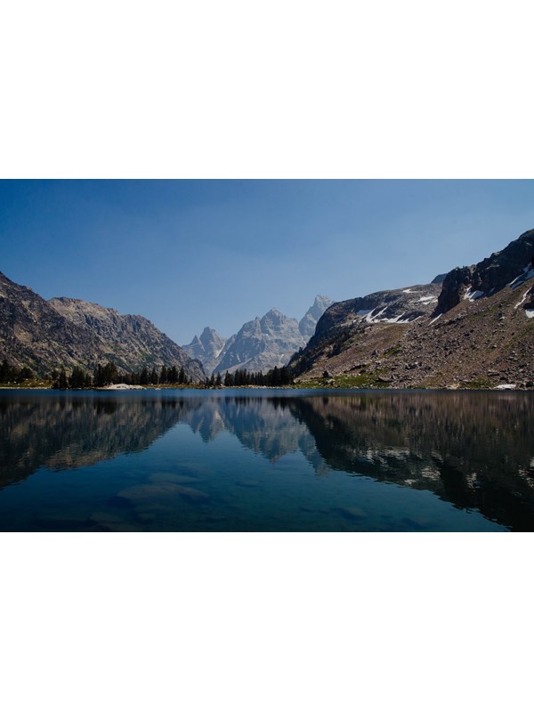 A small lake surrounded by mountains reflects the mountainous scenery on its calm surface.
