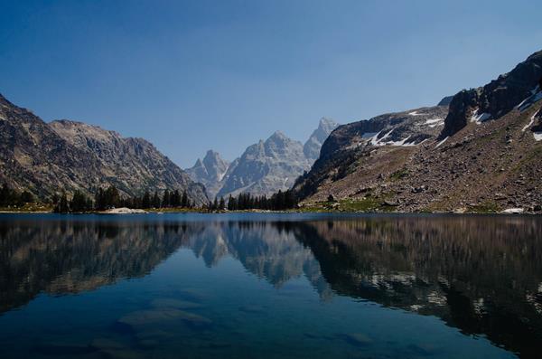 A small lake surrounded by mountains reflects the mountainous scenery on its calm surface.