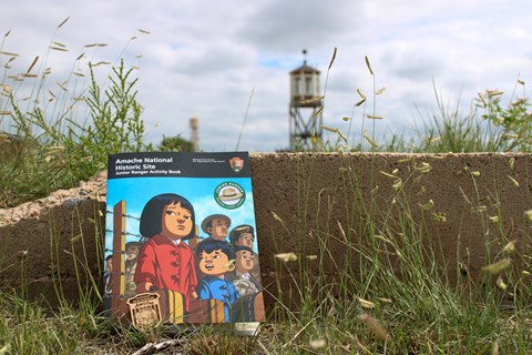A booklet with two cartoon children on the cover leans against a concrete foundation