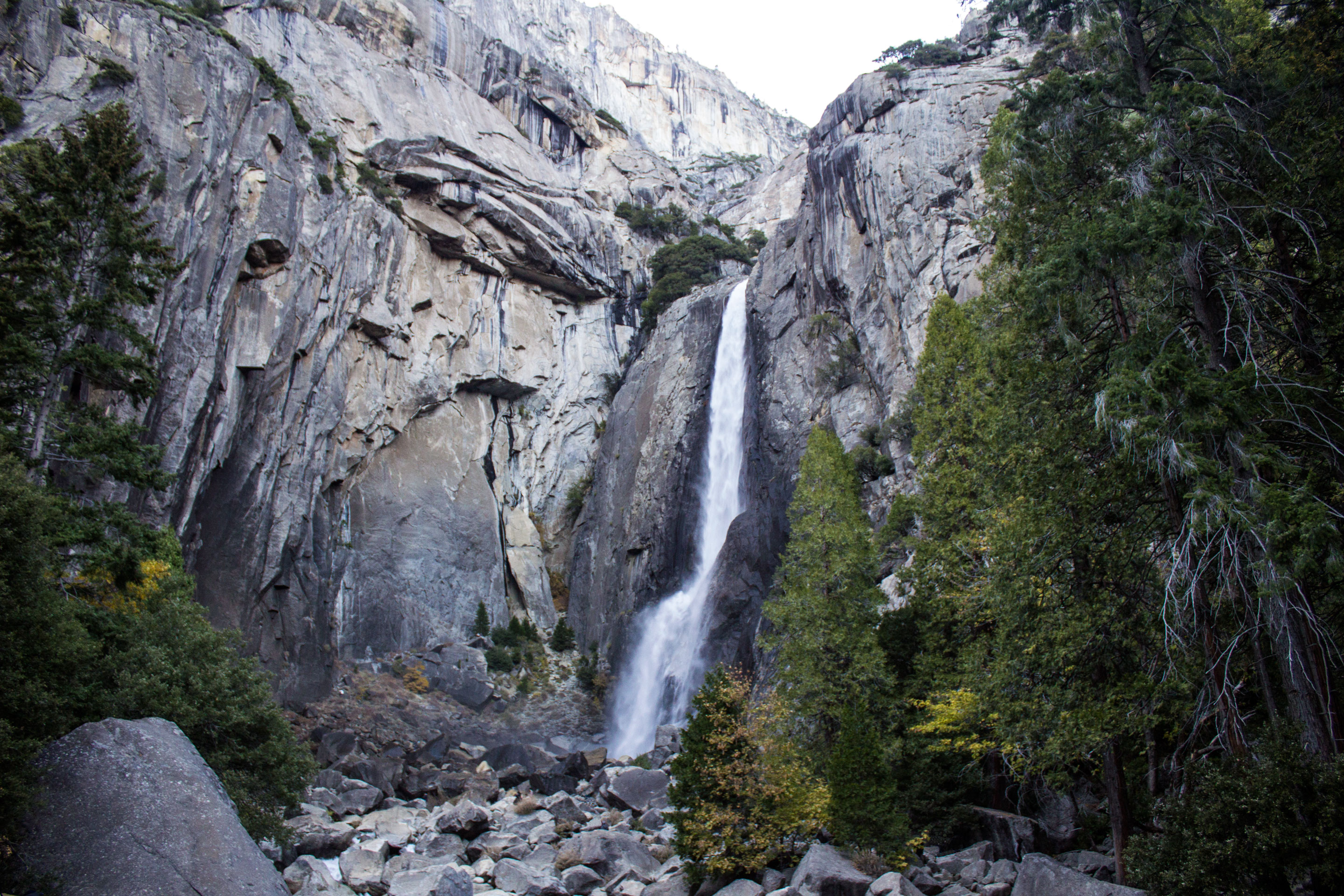 A tall waterfall flows strongly over a cliff and into boulders