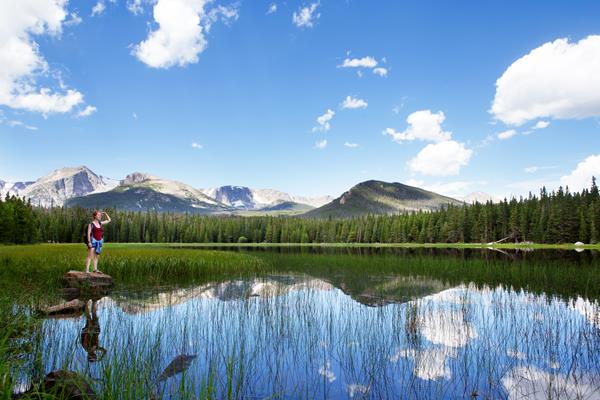 a woman stands on a rock looking out over a lake
