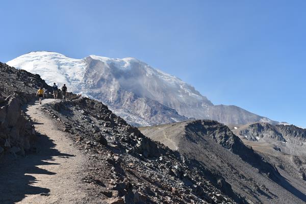 View of glaciated mountain from rolling ridgeline with three rocky peaks.