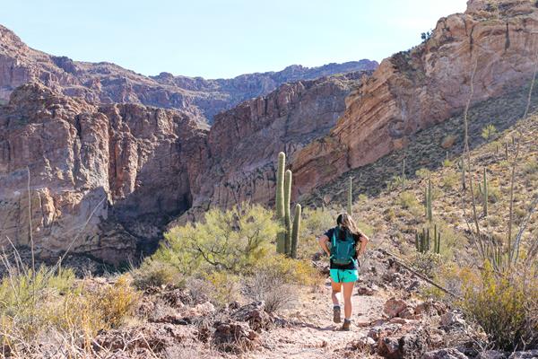 Female visitor hikes on desert trail, surrounded by