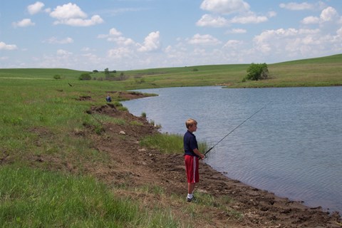 child with fishing pole by pond