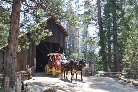 A stage drawn by two horses outside a covered bridge