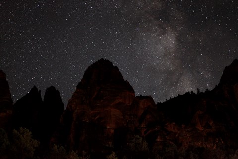 Black silhouette of a triangular mountain under a dark sky full of stars.