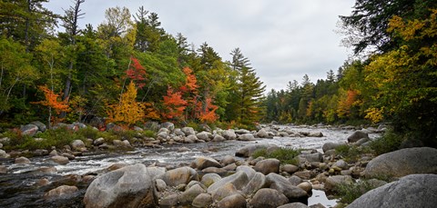 Fall colors line the water at Orin Falls. Red, orange, and yellow trees surround the water.