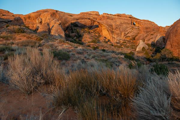 long, skinny sandstone arch in front of a sandstone wall