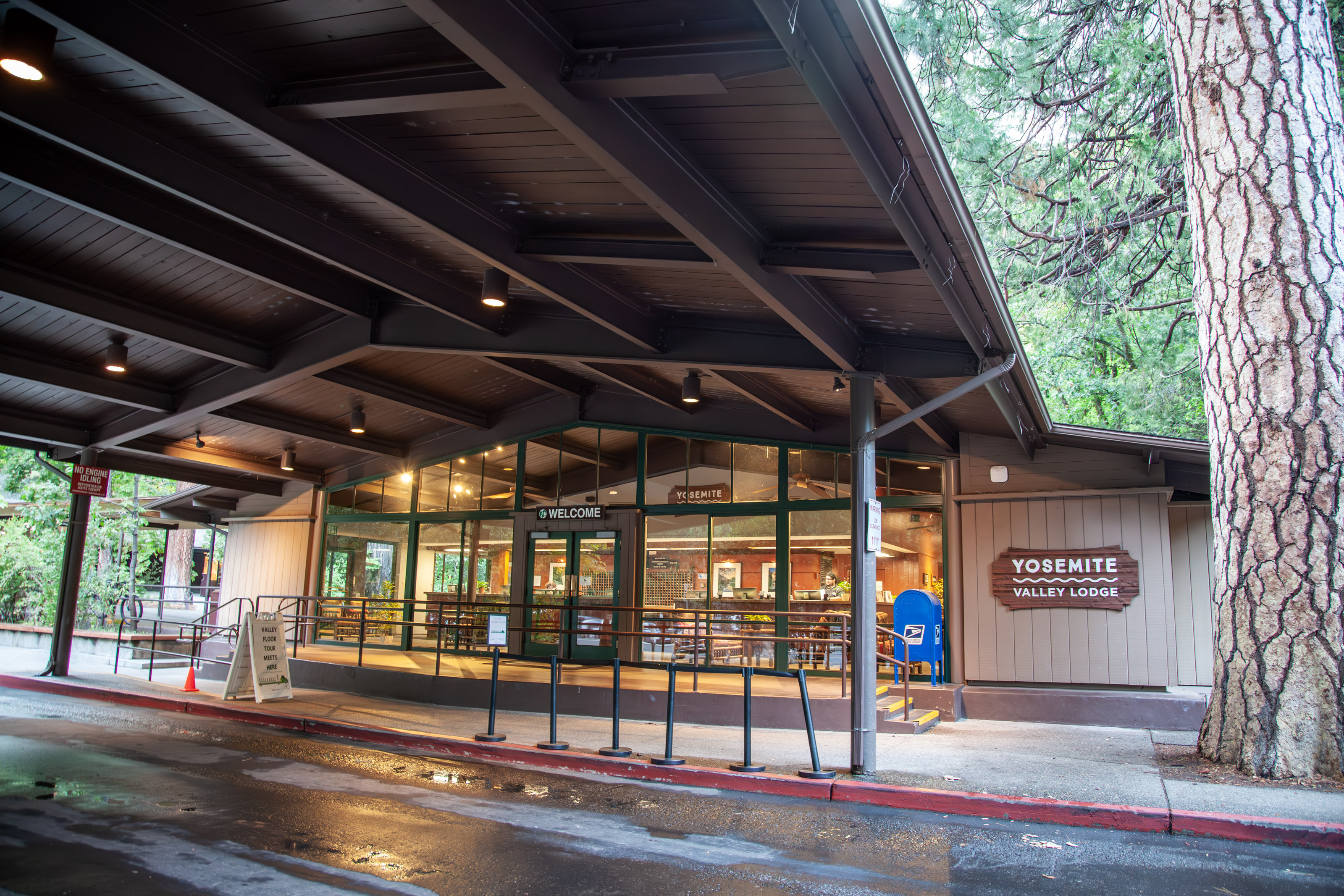 A road leads to a lit building with many windows and a covered entryway