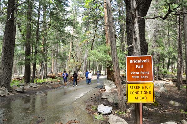 Visitors walking up the paved path from the parking area toward the fall