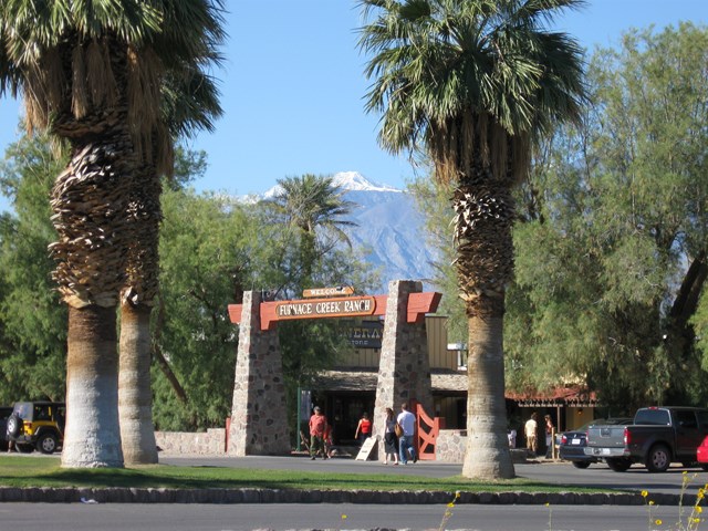 a wooden arch framed by palm trees with mountains in the distance