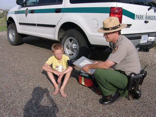 Park Ranger kneels next to a vehicle