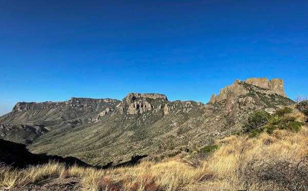 A view to the south encompasses two high peaks and a high, long series of cliffs.